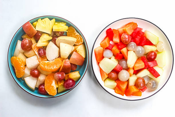 istock fresh fruit salad in plates isolated on white background 2207002084
