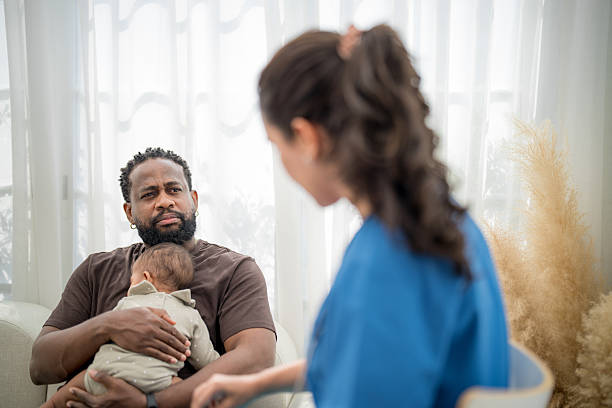 istock Father holds baby while interacting with caregiver in cozy indoor setting during daylight hours 2207003071