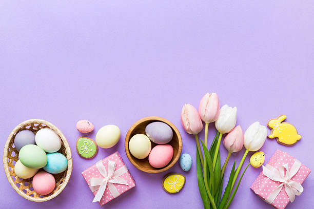 istock Easter frame with eggs, gift box and tulip on a colored background. The minimal concept. Top view Happy Easter composition. Card with a copy space of the place for the text 2207003616