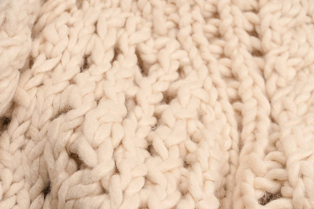 istock A fragment of beige knitted fabric, knitted from white sheep wool. 2207007446