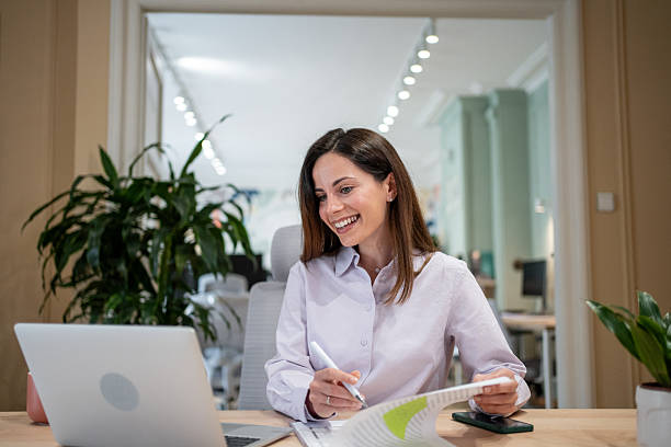 istock Smiling businesswoman analyzing documents and working on a laptop in the office 2207007958