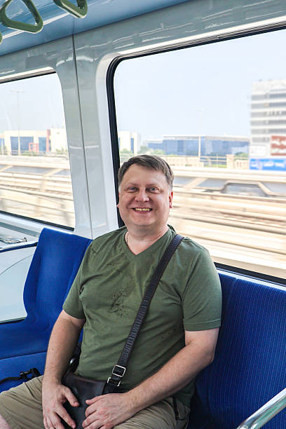 istock Man smiles toothily while sitting in a subway car 2207008553