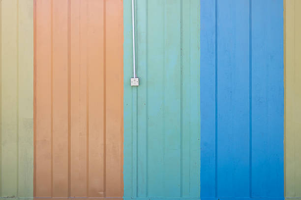 A wall made of iron plates with yellow, orange, green, and blue tints, featuring a light switch in the center