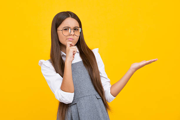 istock Positive teenager child points aside with cheerful expression, shows amazing at blank empty space. Advertisement and mockup. Thinking face, thoughtful emotions of teenager girl. 2207010529