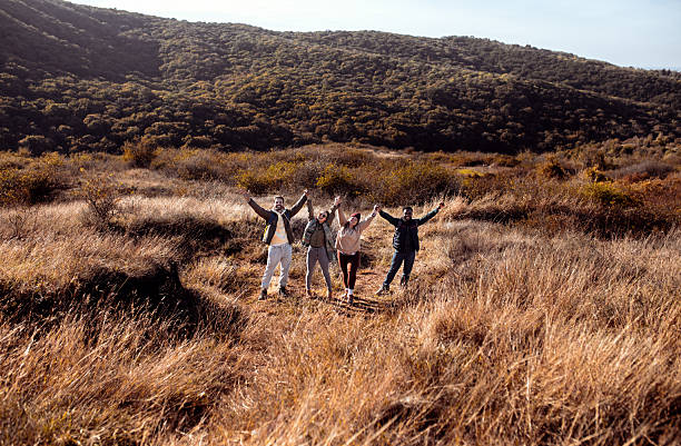 Smiling group of friends having fun while hiking together on hill.