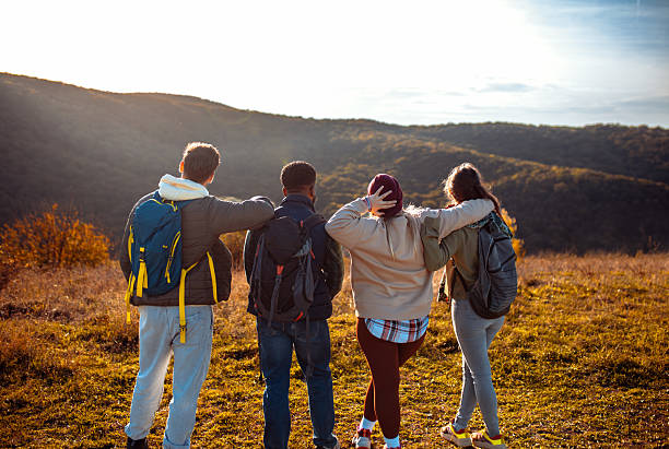 istock Smiling group of friends having fun while hiking together on hill at sunset. 2207013908