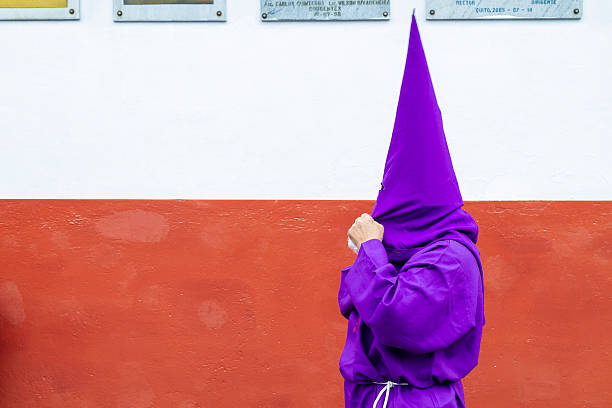 Quito, Pichincha, Ecuador - April 15, 2022: Cucuruchos, members of the brotherhood of Jesus del Gran Poder. They get dressed wearing a purple robe and a conical hood while try to get ready for the procession during a Holy week.