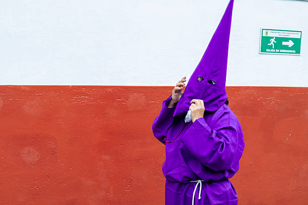 Quito, Pichincha, Ecuador - April 15, 2022: Cucuruchos, members of the brotherhood of Jesus del Gran Poder. They get dressed wearing a purple robe and a conical hood while try to get ready for the procession during a Holy week.