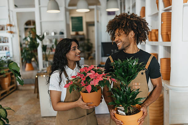 istock Cheerful Couple Holding Potted Plants in Store 2207018879