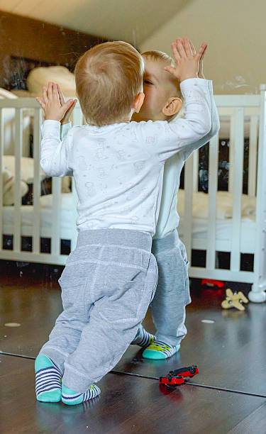 istock A one-year-old baby leaning a mirror, kissing to himself 2207019556