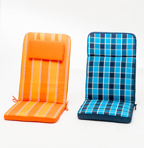 Rows of retro-style outdoor plastic chairs in pastel colors neatly arranged on gravel ground. Each chair features woven stripes in a variety of hues, creating a cheerful and nostalgic seating area.