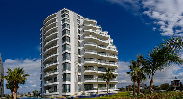 Modern architectural marvel shines under a bright blue sky with palm trees swaying gently in the breeze at a coastal location