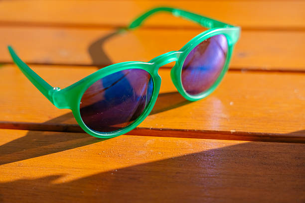Young man holding his sunglasses at La Digue Anse Source d'Argent Rocks Beach. Beach and sea reflecting in the sunglasses. Selective focus on sunglasses. Anse Source d'Argent, La Digue Island, Seychelles