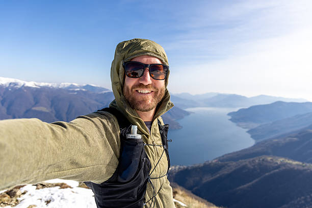 Smiling Hiker Taking Selfie on Mountain Peak with Scenic Lake View
