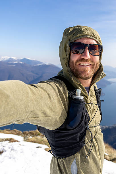 istock Smiling Hiker Taking Selfie on Mountain Peak with Scenic Lake View 2207024389