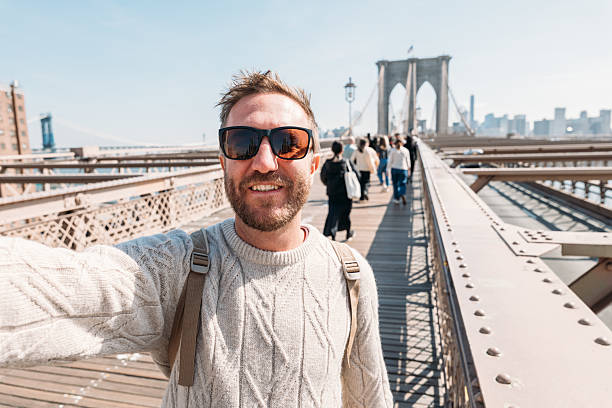 istock Man Taking Selfie on Iconic Bridge with City Skyline 2207025359