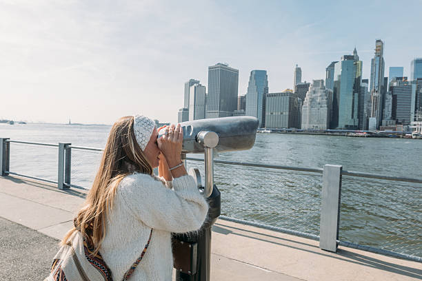istock Woman Observing Cityscape Through Binoculars by the River 2207025466