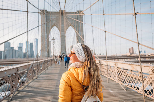 istock Woman in Yellow Jacket Walking on Brooklyn Bridge 2207025633