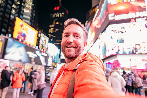 istock Smiling Tourist Taking a Selfie in Times Square at Night 2207025793