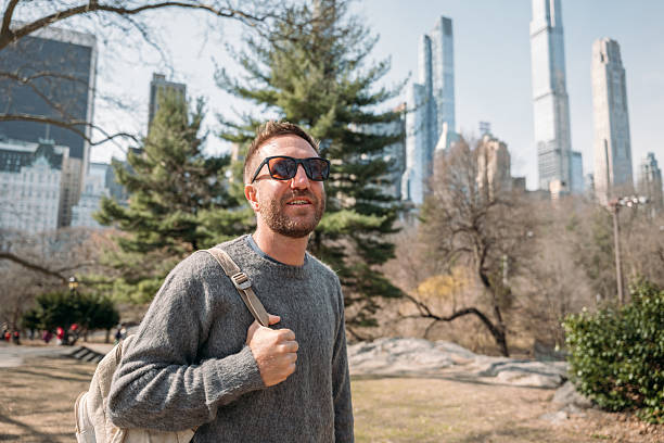 istock Young man enjoying a sunny day in the city with backpack 2207025873