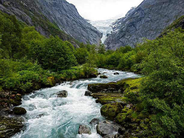Waterfall and meltwater river in the valley approaching Briksdal Glacier in Norway.