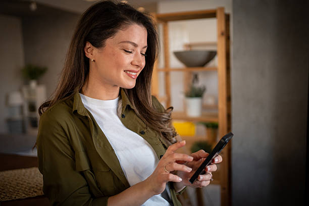 istock Smiling woman using smartphone at home 2207028912