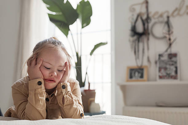 istock Blonde Girl with Down Syndrome Lying on Bed 2207029922