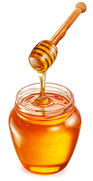 istock Honey dripping from honey spoon into honey pot on white background. File contains clipping path. 2207030217