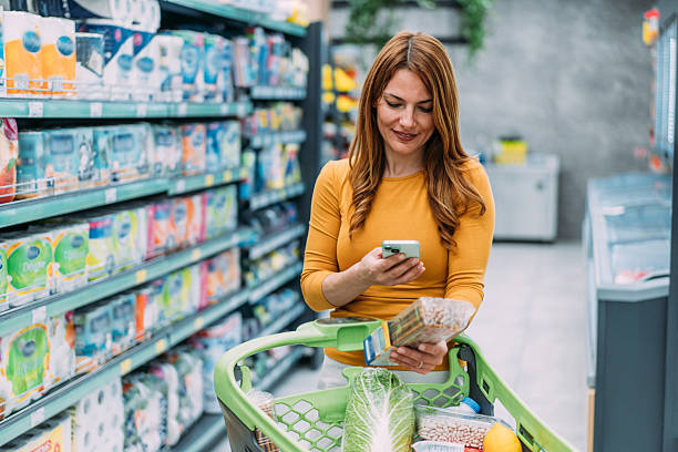 istock Smiling woman scanning QR code on a product while buying in supermarket. 2207030303