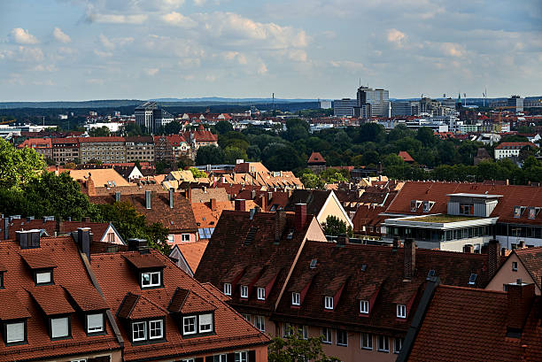 A picturesque cityscape where historic red-roofed houses contrast with modern high-rise buildings in the background. Lush greenery adds a natural touch, blending tradition and urban development harmoniously