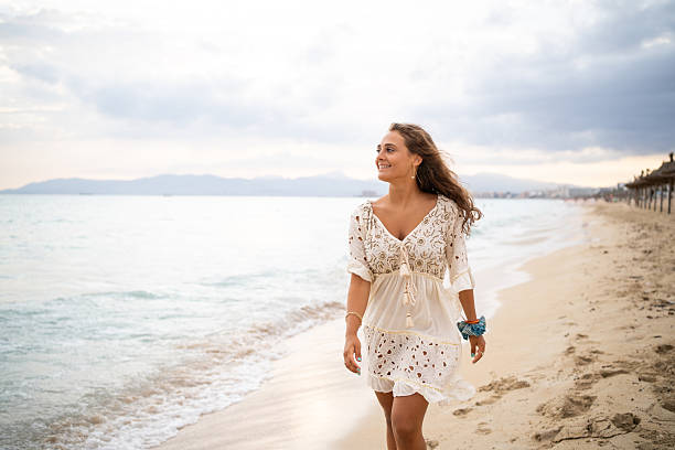 istock Woman walking on the beach at sunset 2207033710