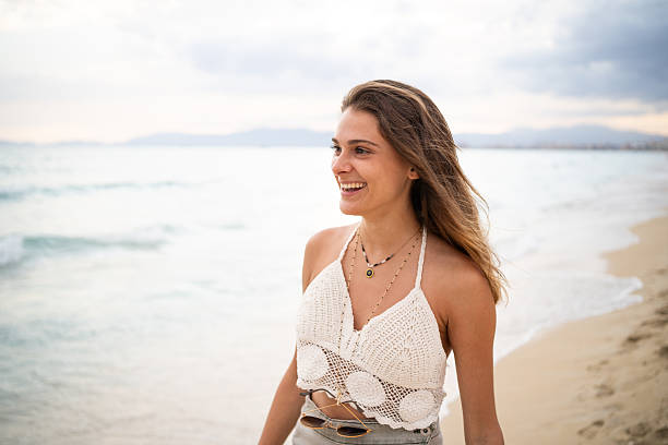 istock Woman walking and smiling on the beach at sunset 2207033759