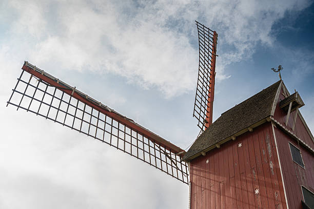 A picturesque windmill with sails against a dramatic cloudy backdrop, perfect for nature and travel themes.