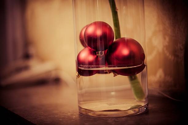 Red decorative Christmas baubles against white brick wall, festive holiday decor emphasizing seasonal spirit and classic ornament style