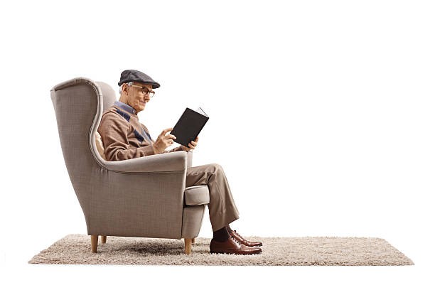 istock Elderly man sitting in an armchair and reading a book 2207036084