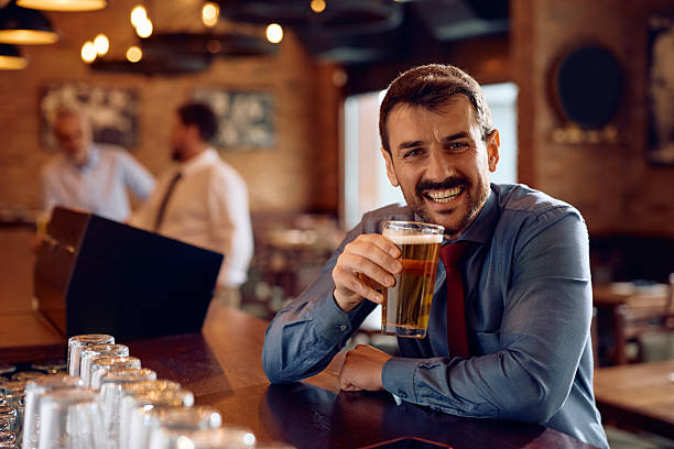 istock Happy businessman drinking beer in a pub and looking at camera. 2207036479