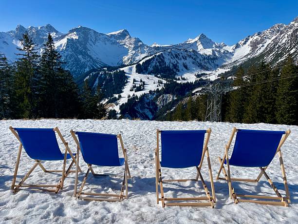Blue deckchairs in snow, breathtaking view of Austrian Alps.