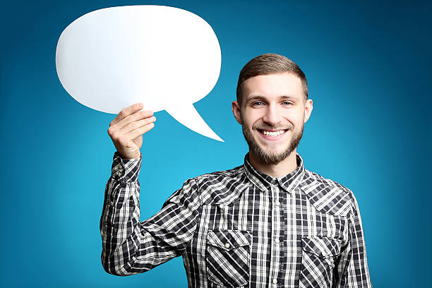 istock Young man holding speech bubble on blue background 2207037345