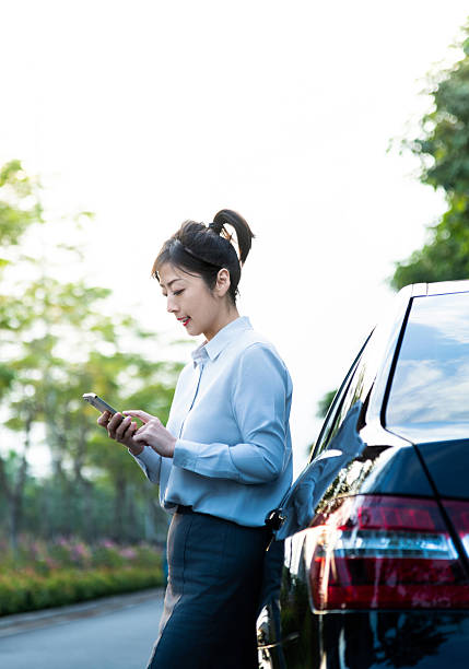 istock Woman leaning on car and using mobile phone 2207037694