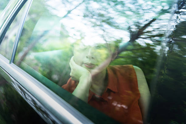 Woman in car driving through a forest