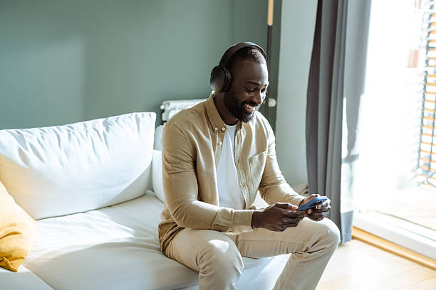 istock Man relaxing at home, using technology on devices with headphones, enjoying leisure 2207040375
