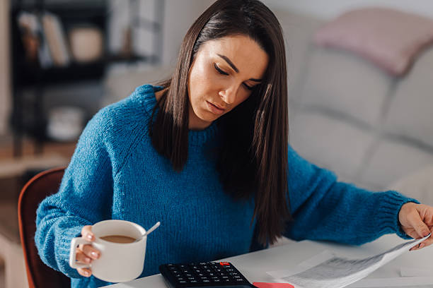 istock Woman drinking coffee and managing home finances with calculator and documents 2207041937