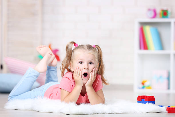 istock Little girl lying on white carpet at home 2207043410