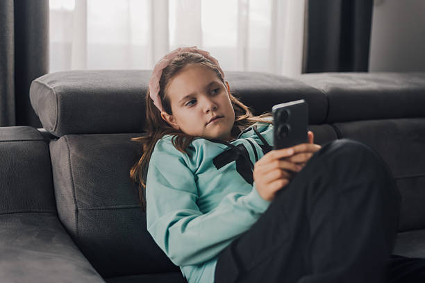 istock Young girl using smartphone while relaxing on sofa at home 2207045608