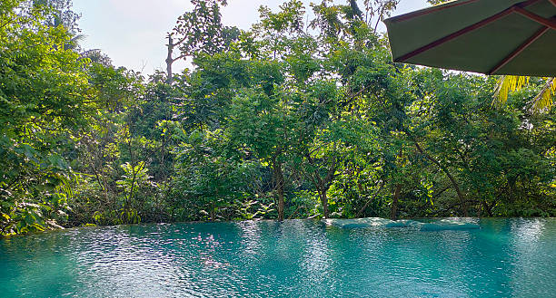 A beautiful woman jumps into a swimming pool that overlooks the Pacific Ocean in Guanacaste, Costa Rica.