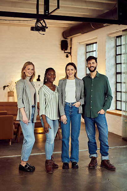 istock Group of Four Smiling Professionals Posing Together in Modern Office Setting 2207047392