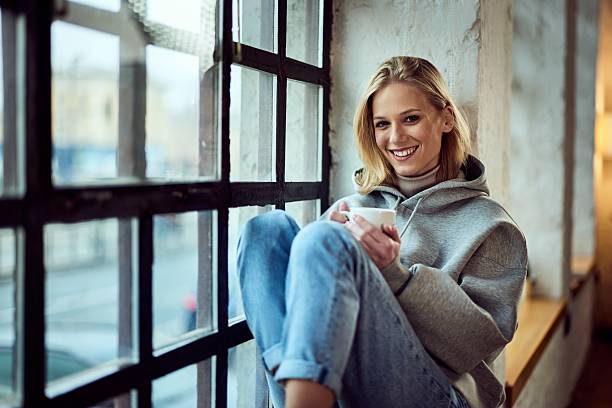 istock Relaxed Woman Enjoying Coffee by Large Window in Cozy Modern Interior 2207047443
