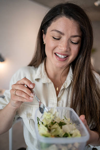 istock Young woman enjoying a healthy salad at work 2207050958