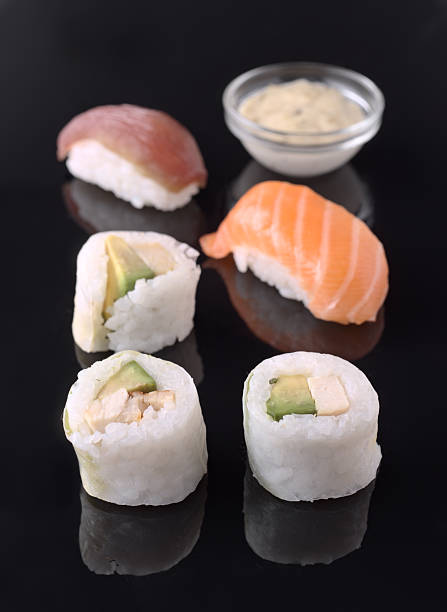 istock Delicious sushi assortment with salmon, tuna, and avocado rolls on black reflective surface 2207053997