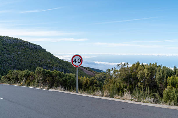 A smooth, curving road stretches through a mountainous region, marked by a 40 km h speed sign. The untouched nature offers a serene escape.